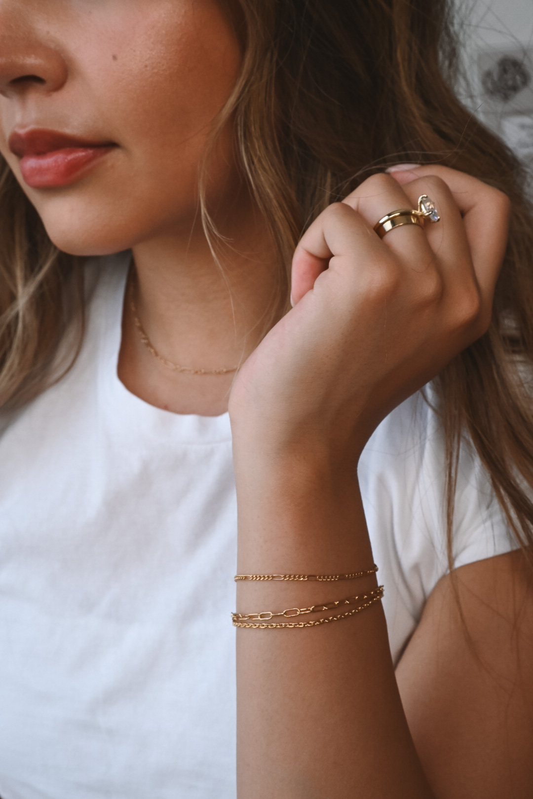 Two friends wearing matching permanent gold bracelets